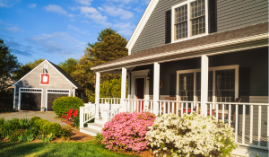 Beautiful suburban home with a new roof, stone siding, and vibrant landscaping along a curved walkway.